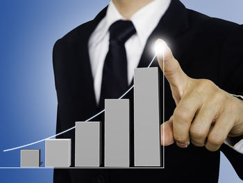 Midsection of man holding cigarette against gray background