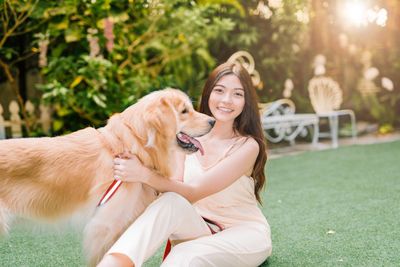 Portrait of smiling woman with dog sitting in park