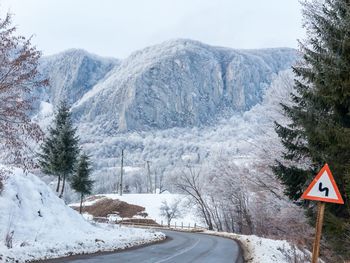 Road by mountains against sky during winter