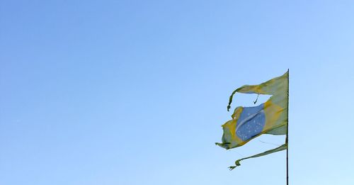 Low angle view of flag against clear blue sky