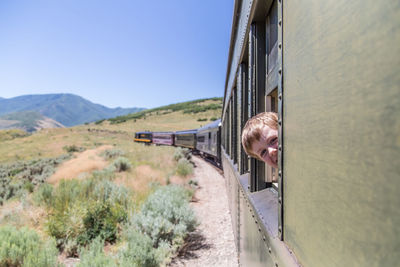 Side view of train at railroad track against clear sky