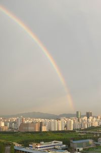 Rainbow over buildings in city against sky