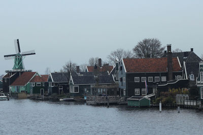 Buildings by river against clear sky