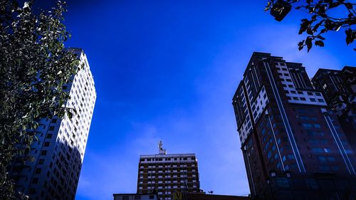 Low angle view of modern buildings against blue sky