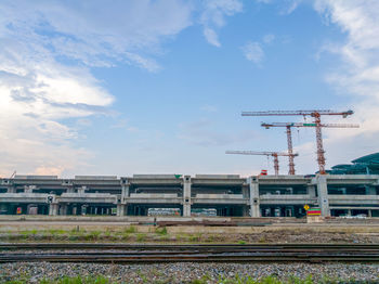 Railroad tracks by construction site against sky