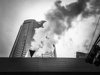 Low angle view of smoke by modern building against sky