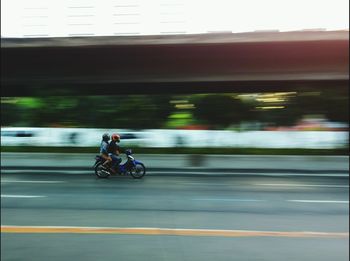 Blurred motion of man riding bicycle on road