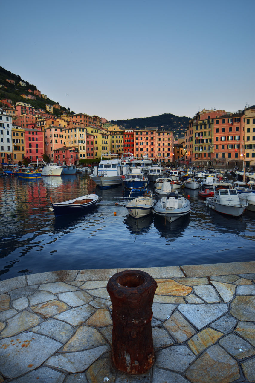 BOATS MOORED IN RIVER BY BUILDINGS AGAINST SKY