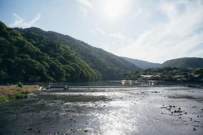 Scenic view of river by mountains against sky