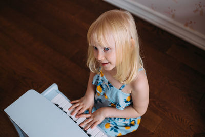 Little blonde girl plays a toy piano at home. musical development in childhood