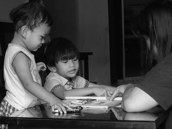 Cute baby boy and old brother at home learning how to read alfabet from mother