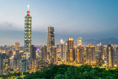 Illuminated buildings in city against sky