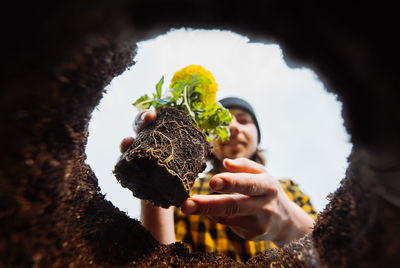 Male gardener holding flowers. view from below.