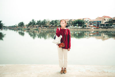 Portrait of young woman standing in lake against clear sky