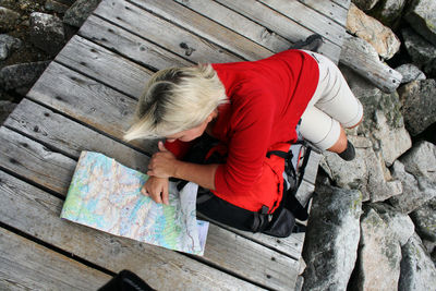 High angle view of female hiker with map on boardwalk