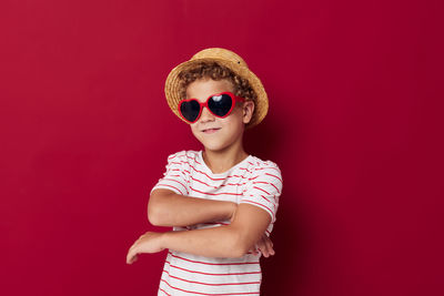 Portrait of boy wearing sunglasses against red background