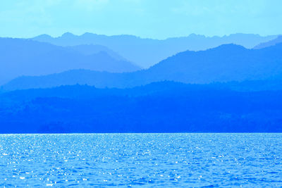 Scenic view of sea and mountains against blue sky