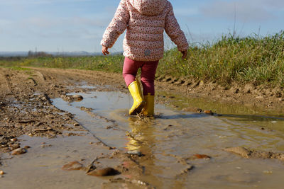 Low section of girl walking in mud