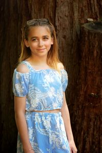 Portrait of smiling girl standing against tree trunk