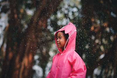 Cute girl looking away while standing during raining season