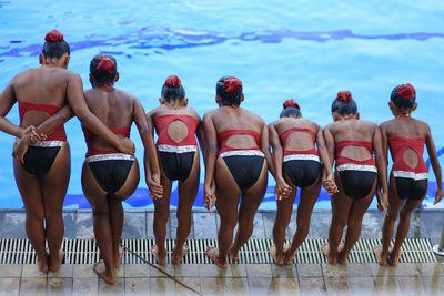 Rear view of girls standing by swimming pool