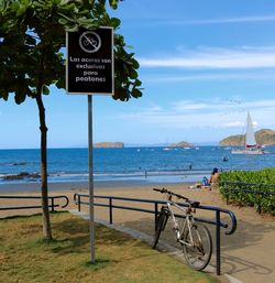 Bicycle parked by sign board at beach