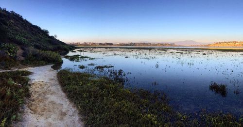 Scenic view of calm lake against clear blue sky