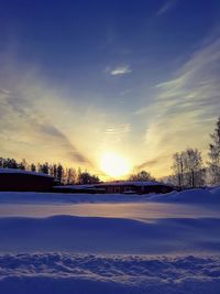 Scenic view of snow covered field against sky during sunset