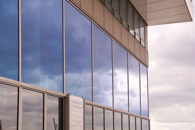 Low angle view of glass building against sky