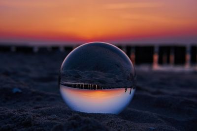 Close-up of crystal ball on beach during sunset