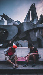 People sitting on bridge against buildings in city