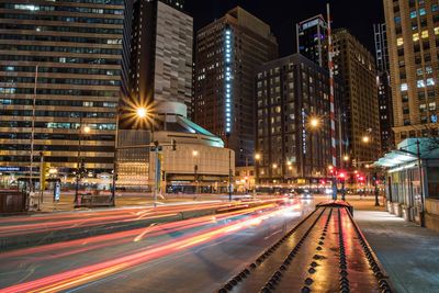 Light trails on city street by buildings at night