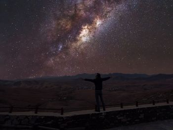 Man standing on field against sky at night