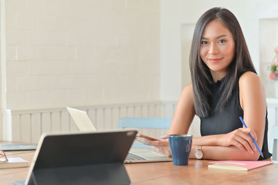 Portrait of a smiling young woman using phone