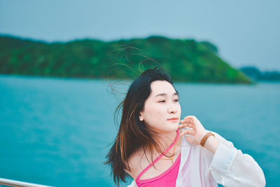 Portrait of young woman against sky