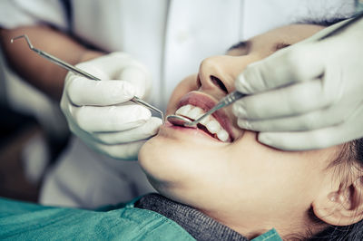 Close-up of young woman getting her teeth examined by dentist