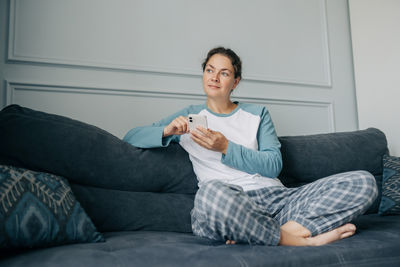 Portrait of young woman sitting on bed at home
