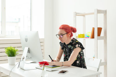 Young woman using mobile phone while sitting on table