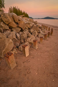 Rocks on beach against sky during sunset