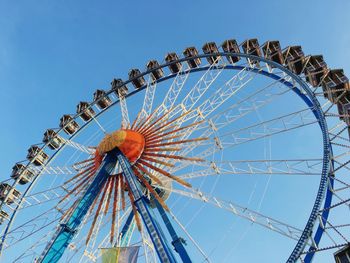 Low angle view of ferris wheel against clear blue sky