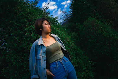 Beautiful young woman looking away while standing on land