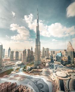 Aerial view of buildings in city against cloudy sky