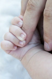Cropped image of baby holding father hand