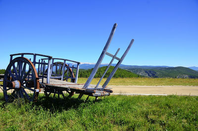Low angle view of abandoned cart against blue sky