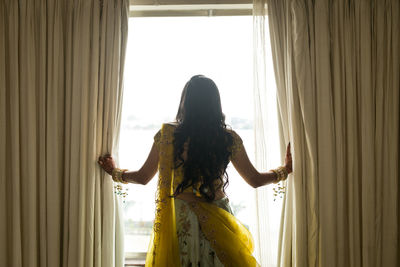 Rear view of woman standing by window