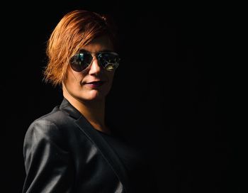 Portrait of smiling young woman against black background