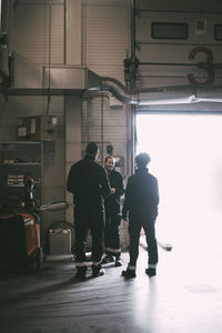 Female and male colleague planning while standing by entrance of warehouse