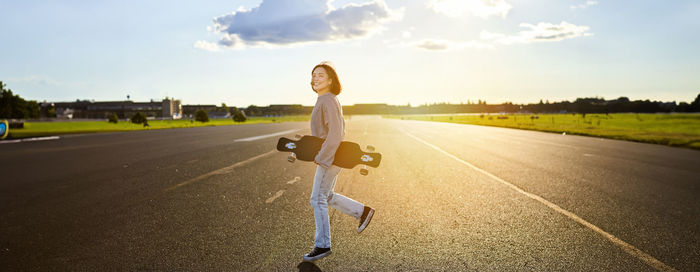 Rear view of woman walking on road against sky