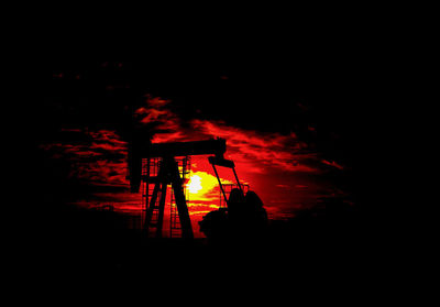 Low angle view of silhouette illuminated light on field against sky at night