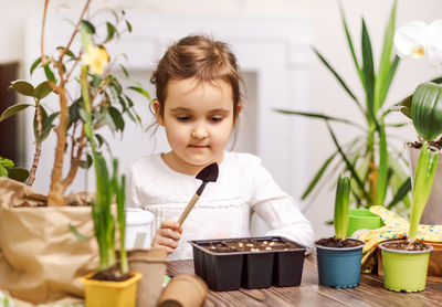 Portrait of young woman holding potted plant